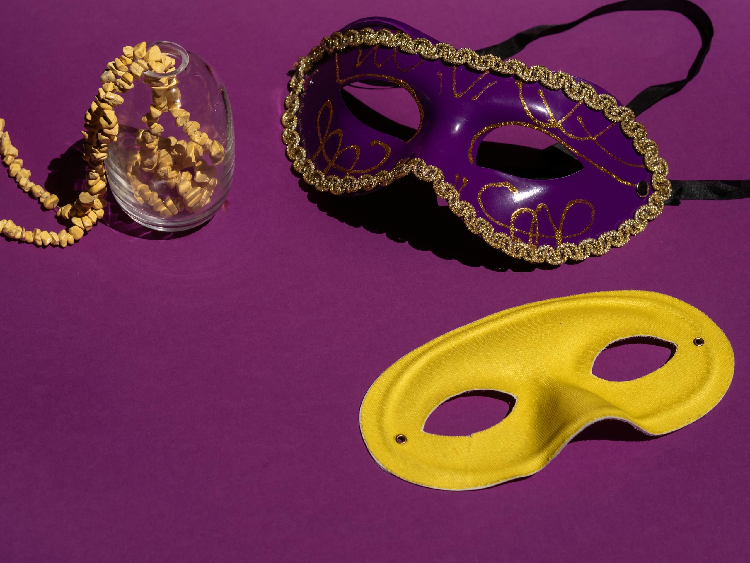 Colorful Mardi Gras masks showcase elegance with a purple and yellow contrast on a violet background.